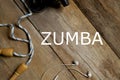 Top view of skipping rope,earphone and water bottle on wooden background written with Zumba. Health and fitness concept. Royalty Free Stock Photo