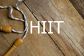 Top view of skipping rope on wooden background written with HIIT. Fitness, healthy and active lifestyles concept