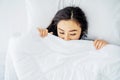 Top view of sleeping asian woman cover face with blanket flat lay. Close-up of young women, sleeping under white blanket Royalty Free Stock Photo