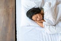 Top view of a sleeping asian woman. She lies under the duvet and hugs the pillow. Royalty Free Stock Photo