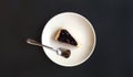 Top view of slice of blueberry cheesecake and stainless steel spoon in white dish or plate on black background with copy space.