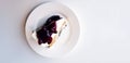 Top view of slice of blueberry cheesecake on white dish or plate with copy space on right.