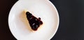 Top view of slice of blueberry cheesecake on white dish or plate with copy space on right.