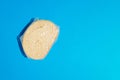 Top view of slice of fresh white bread with sesame seeds wrapped in foil against blue background. Copy space Royalty Free Stock Photo