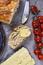 Slice of fresh wholewheat bread with butter between plate with cheese and fresh tomatos