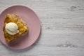 Top view, slice of homemade apple pie with ice cream on a pink plate over white wooden surface, top view. Copy space Royalty Free Stock Photo