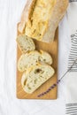 Top View of Sliced Artisan Rustic Bread on Wooden Cutting Board White Line Table Cloth Lavender Twig. Golden Crust Royalty Free Stock Photo