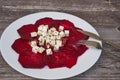 Top view on sliced baked beetroot appetizer salad with with fork and knife on wooden table. Royalty Free Stock Photo