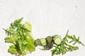 Top view of sliced cucumber,lettuce, arugula on the white surface.Empty space for text. Differnt green ingredients for salad, nat