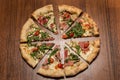 top view of sliced in eight pieces of pizza with arugula, ham, and tomatoes