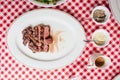 Top view of Sliced medium rare charcoal grilled wagyu Ribeye steak in white plate on red and white pattern tablecloth with cutlery Royalty Free Stock Photo