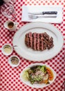 Top view of Sliced medium rare charcoal grilled wagyu Ribeye steak in white plate on red and white pattern tablecloth. Royalty Free Stock Photo