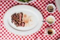 Top view of Sliced medium rare charcoal grilled wagyu Ribeye steak in white plate on red and white pattern tablecloth.