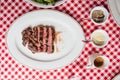 Top view of Sliced medium rare charcoal grilled wagyu Ribeye steak in white plate on red and white pattern tablecloth. Royalty Free Stock Photo