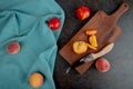 top view of sliced peach with knife on cutting board with whole peaches on cloth on brown and black background Royalty Free Stock Photo