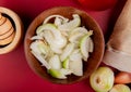 top view of sliced white onion in bowl with whole ones spilling out of sack and black pepper in garlic crusher on red background Royalty Free Stock Photo