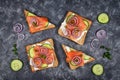 Top view of slices of healthy wholegrain toast bread topped with smoked salmon fish, red onions and spring onions and cucumber on Royalty Free Stock Photo