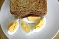 Top view of slices of toasted whole wheat bread with boiled eggs on a plate for breakfast