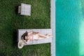 Top view of slim woman in beige bikini take sunbath on lounge chair at the poolside near luxury pool in tropic on vacation Royalty Free Stock Photo