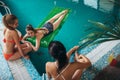 Top view of slim young female friends relaxing at hotel swimming pool