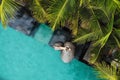 Top view of slim young woman in beige bikini and straw hat relaxing near luxury swimming pool and palm trees.Vacation Royalty Free Stock Photo