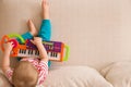 Top view on small cute toddler boy sitting on the sofa and playing on the toy piano. A little boy learning to play piano