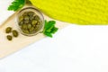 Top view of small green pickled capers fruit in a glass dip bowl on light wooden background in the kitchen with copy space. Royalty Free Stock Photo