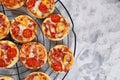 Top view of small mini pizzas topped with cheese, tomato, yellow and red bell peppers and salami sausage on round black grid Royalty Free Stock Photo