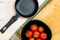 Top view of small pan and fresh ripe cherry tomatoes in small black bowl on a rustic white wooden table. Ingredients and food Royalty Free Stock Photo