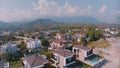 Top view of small resort town. Hotels, houses and roads. Green hills around. Rooftops. Panorama.