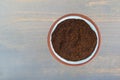 Top view of a small terracotta spice bowl filled with chili powder on a blue painted wood background