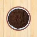 Top view of a small terracotta spice bowl filled with chili powder on a wood background