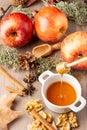 Top view of small white bowl with honey, red royal gala apples with cinnamon sticks, walnuts and autumn leaves, with selective foc