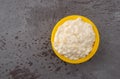 Top view of a small yellow bowl of pineapple cottage cheese on a gray table