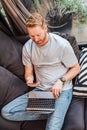Top view of smart modern casual man using smart phone and laptop while comfortably sitting on sofa at home or home office working Royalty Free Stock Photo