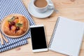 top view of Smart phone with notebook and cup of latte art coffee on wooden background. Royalty Free Stock Photo