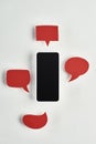 Top view of smartphone with blank screen on white background near empty red speech bubbles, cyberbullying concept.