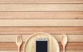 Top view smartphone on wooden dish on wooden plank background