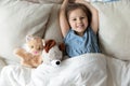 Top view smiling cute girl lying in bed with toys Royalty Free Stock Photo