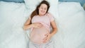 Top view of smiling pregnant woman lying on bed stroking and looking on her big belly. Concept of pregnancy, preparing Royalty Free Stock Photo