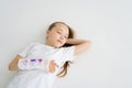 High-angle view of positive sweet little girl with broken hand wrapped in plaster bandage with colorful draw lying on Royalty Free Stock Photo