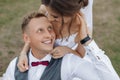 Top view of smiling wedding couple sitting on green grass in park in summer. Young pretty woman bride hugging young man. Royalty Free Stock Photo