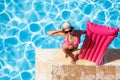 Woman with pink inflatable mattress at poolside