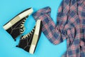 Top view of sneakers and a plaid shirt on a blue background