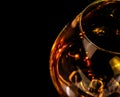 Top of view of snifter of brandy in elegant typical cognac glass on black background with red reflection