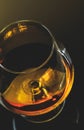 Top of view of snifter of brandy in elegant typical cognac glass on dark background with golden reflection