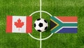 Top view soccer ball with Canada vs. South Africa flags match on green football field