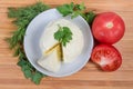 Top view of soft cheese ball on saucer, tomatoes, greens Royalty Free Stock Photo