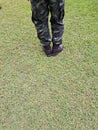 Top view, soldier in training uniform and combat boots standing on green grass.