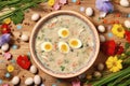 Top view of sour Polish Easter soup, Zurek with hard-boiled eggs and vegetables and herbs in a plate. Wooden background decorated